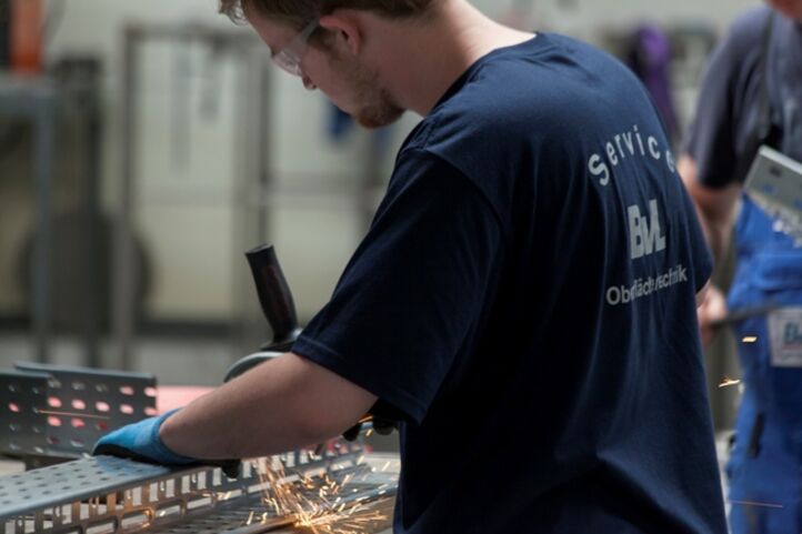 BvL Oberflächentechnik-Mitarbeiter bei der Arbeit mit einem Winkelschleifer und Schutzkleidung